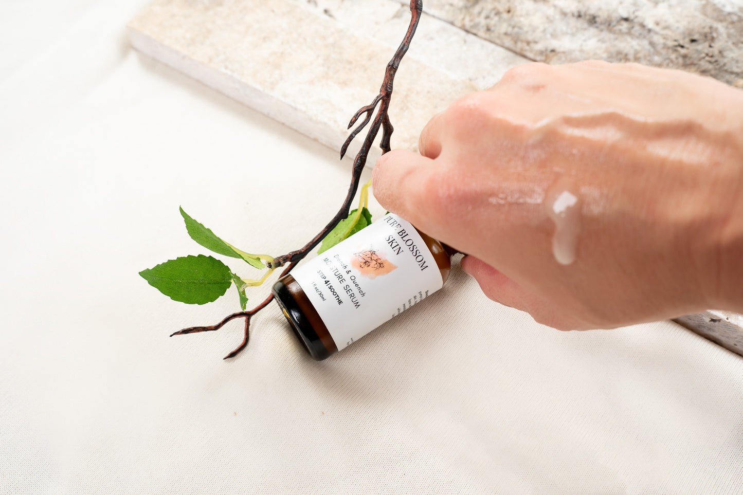 Close up of back of hand with milky rich serum dripping down. 1oz amber glass bottle of Drench & Quench MOISTURE SERUM under hand | Pure Blossom Skin