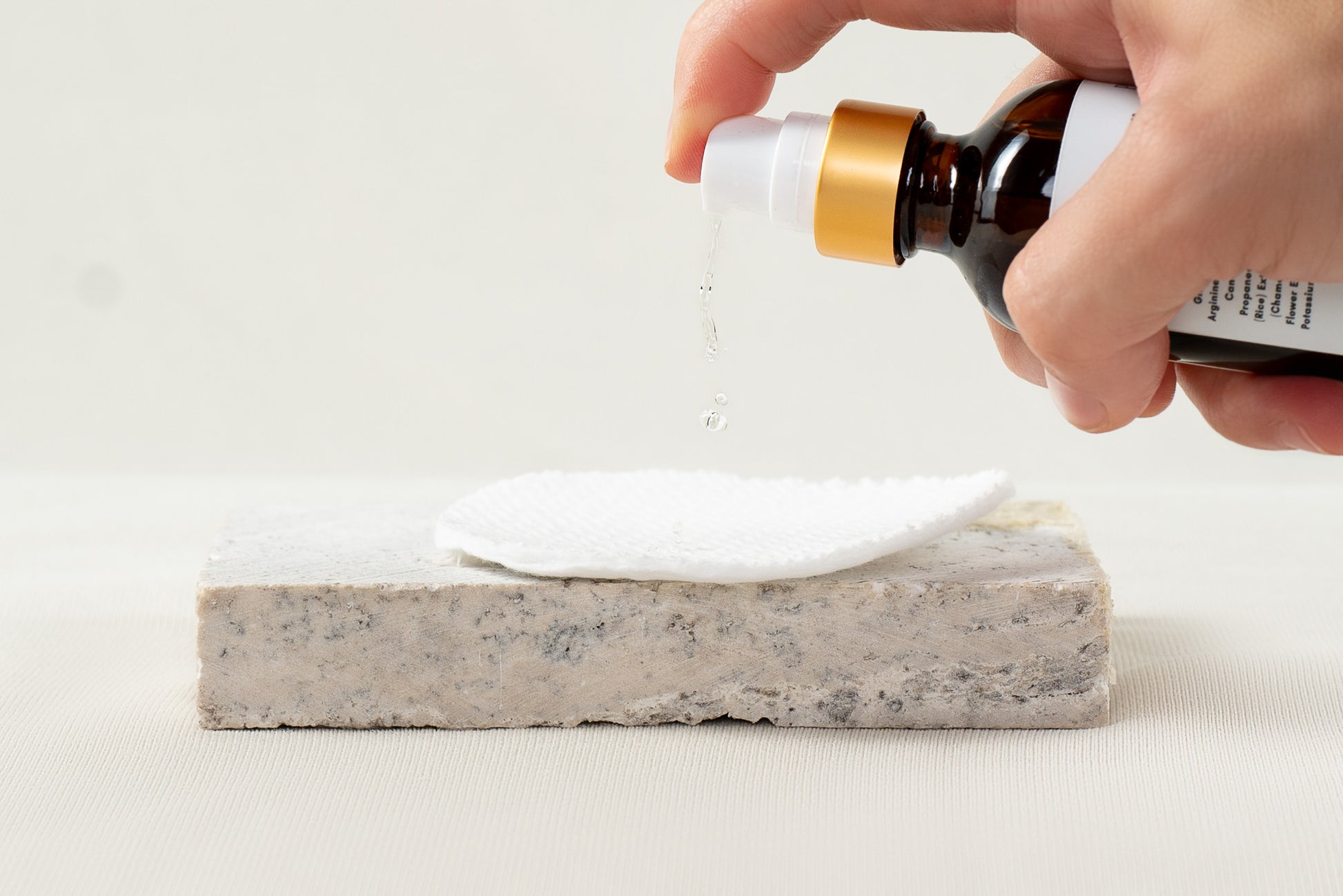 2oz pump amber glass bottle w/gold matte trim, pumping TONER onto cotton round | Pure Blossom Skin